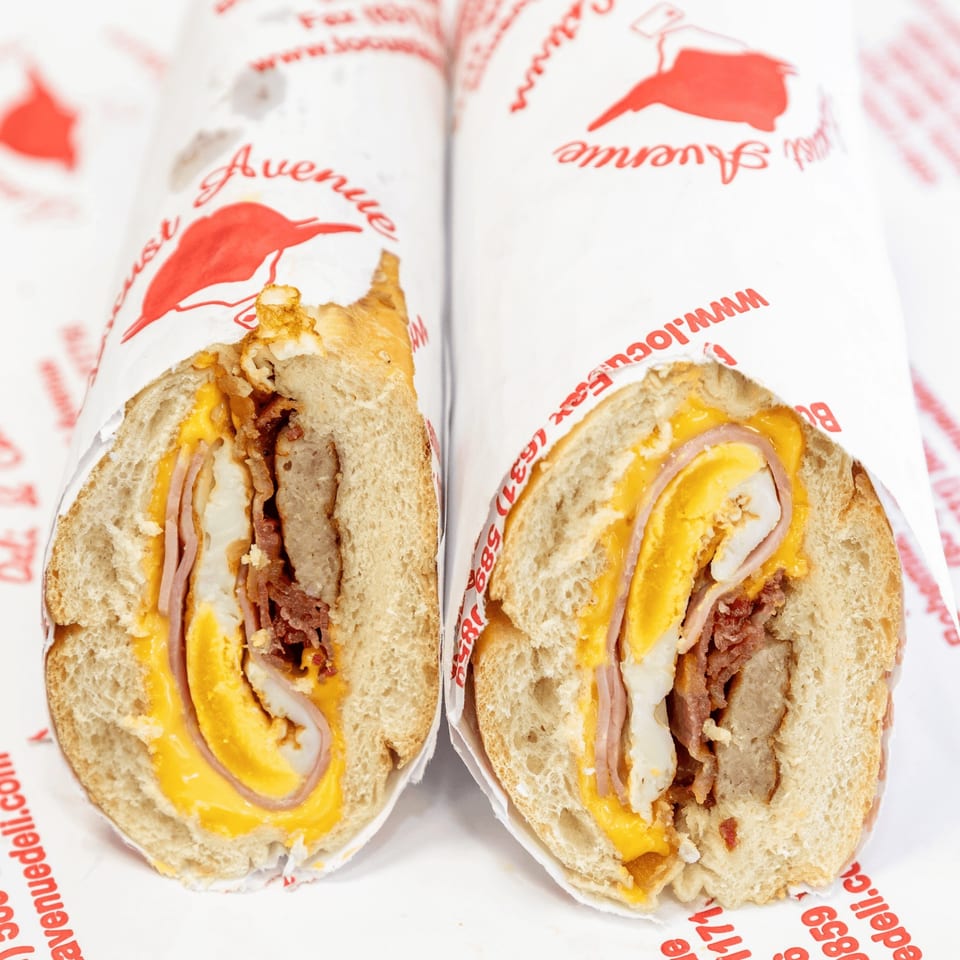 Two halves of a Locust Avenue Deli breakfast sandwich with egg, cheese, ham, and bacon.